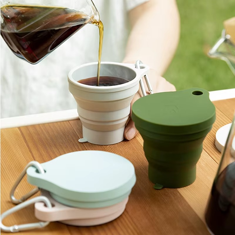 The GoCup™ - Collapsible Travel Mug in multiple colors being filled with coffee, ideal for eco-conscious coffee lovers who enjoy drinks anywhere.